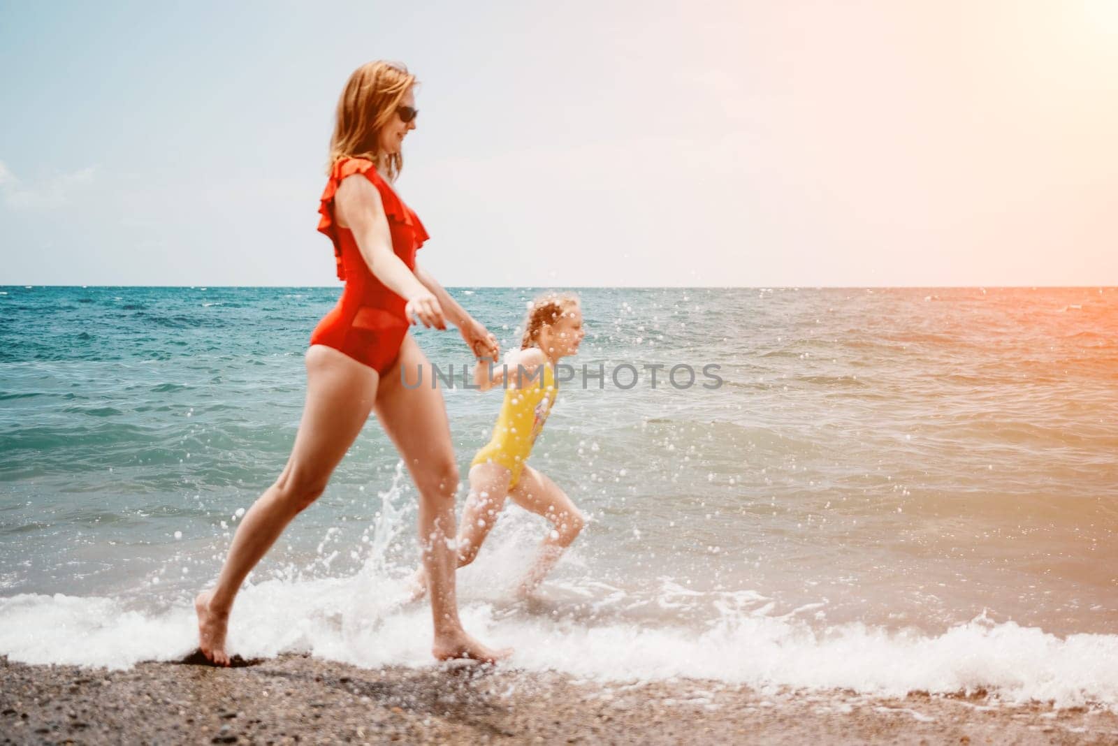 Happy loving family mother and daughter having fun together on the beach. Mum playing with her kid in holiday vacation next to the ocean - Family lifestyle and love concept by panophotograph