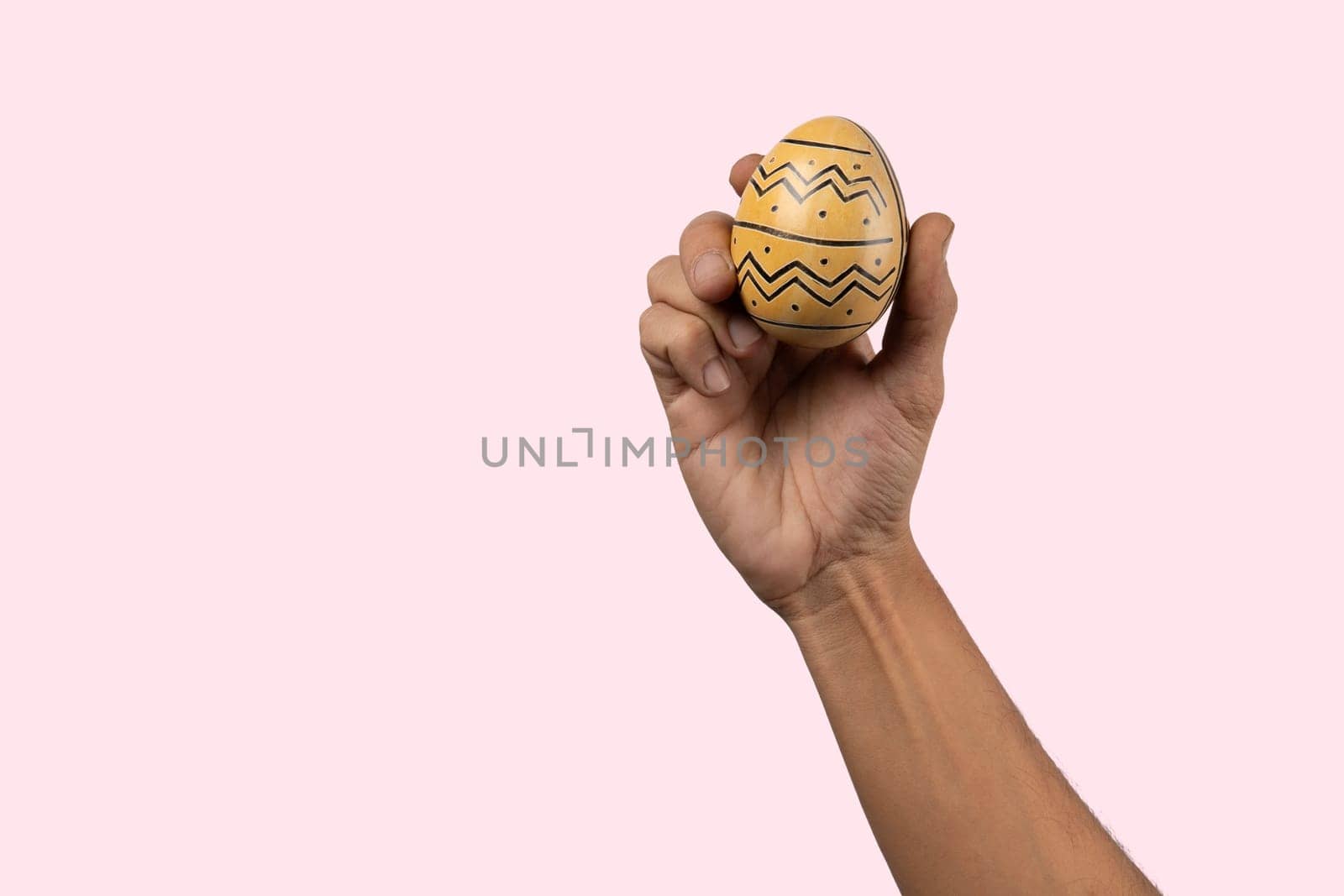 Male hand holding modern painted easter egg on pink background. by TropicalNinjaStudio