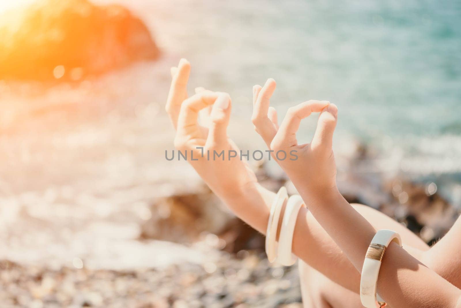 Close up Yoga Hand Gesture of Woman Doing an Outdoor meditation. Blurred sea background. Woman on yoga mat in beach meditation, mental health training or mind wellness by ocean, sea by panophotograph