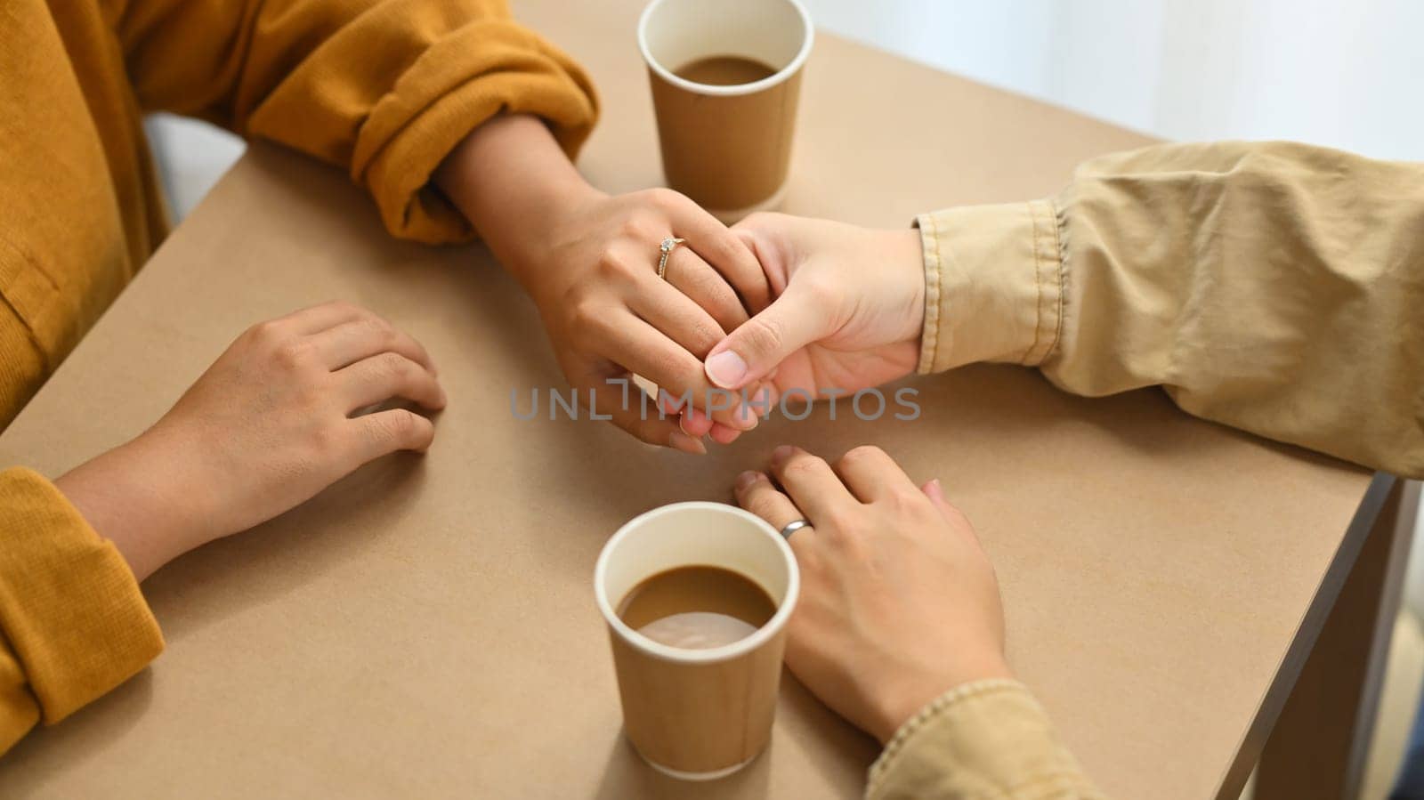 Married couple holding hands and drinking coffee at cafe. Love, relationship and lifestyle concept.