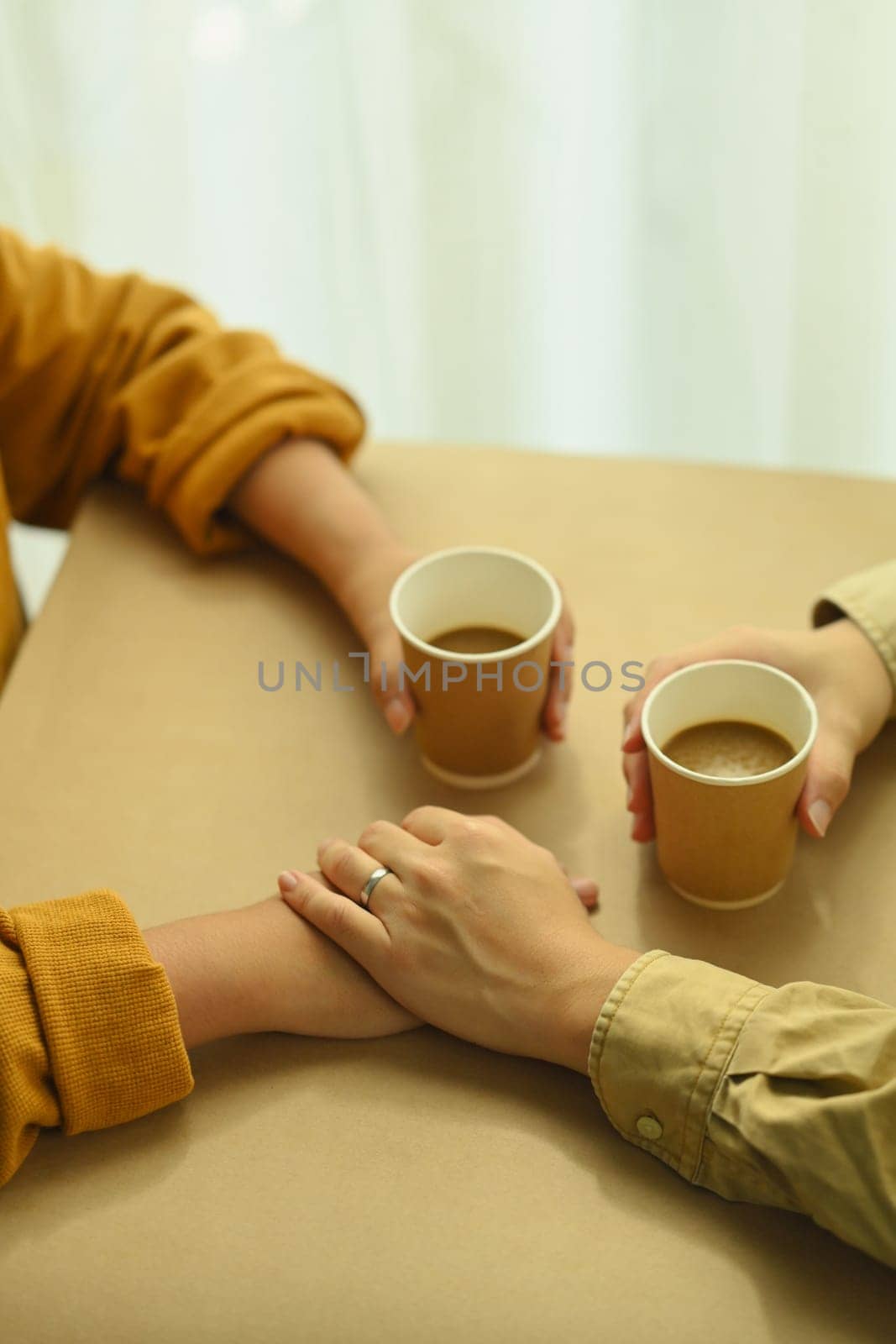 Young lovers having a coffee time while holding hands. Love, relationship and lifestyle concept by prathanchorruangsak