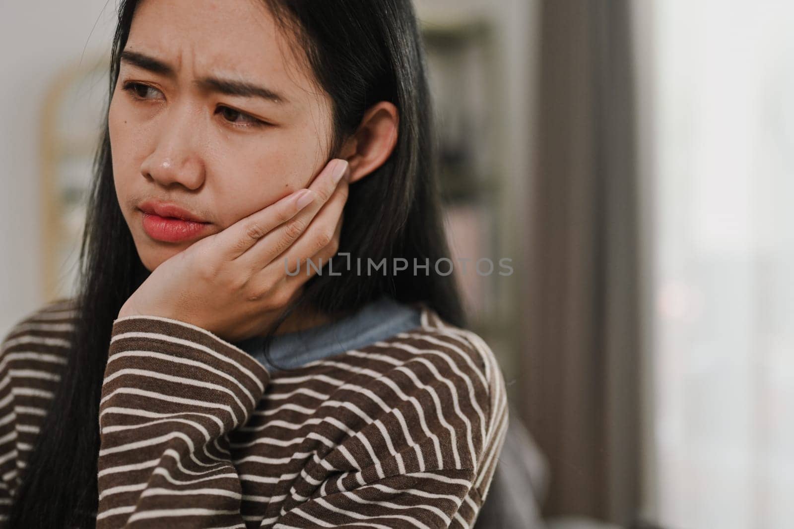 Young woman suffering acute toothache, touching her cheek with painful expression. Dental Care concept.