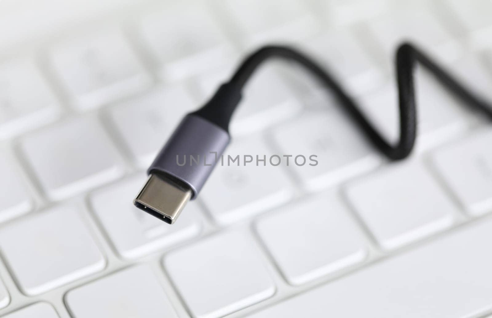 Close up, on computer keyboard cord with adapter. Usb input for tablet lies on keyboard. Self-training on computer and accessories. External sound card for laptop. Wire to connect to device