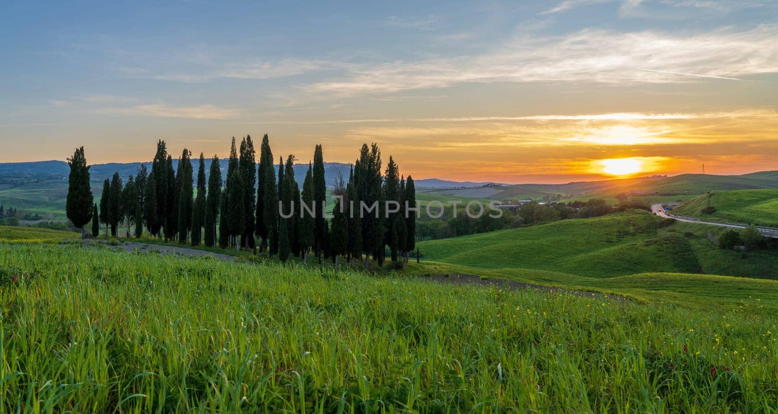 Path to hill house through cypress trees and sunrise view of stunning rural landscape of Tuscany, Italy