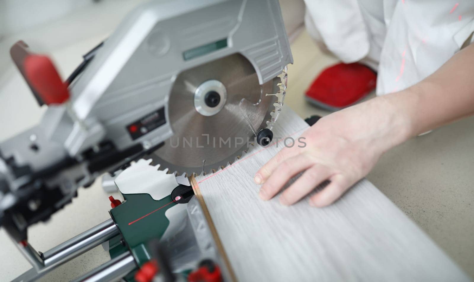 Man uses circular saw table while cutting laminate. Laminate laying technology with Click lock. Features of sawing laminate. Flooring option. Imitation shades and textures various types wood