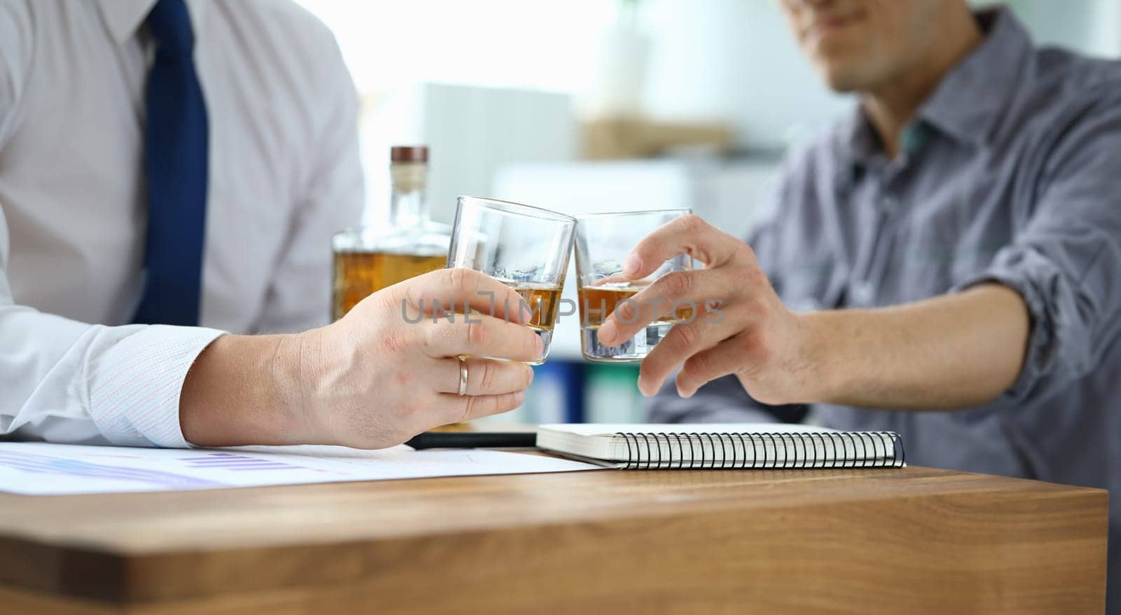 Men in suits drink alcohol in workplace at office. Communication business partners and solving important issues. Person is addicted to alcohol. Signing of an agreement on overcoming financial crisis