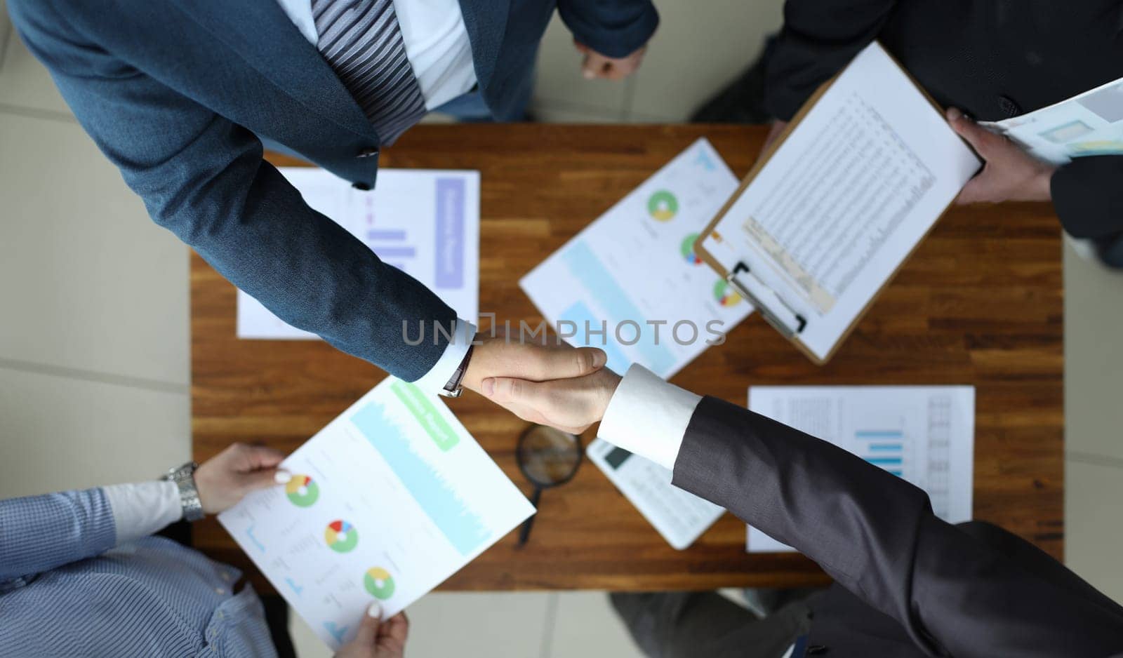 Men shake hands over the table with reports. Marketing and branding add value and attract new customers. Launching and calculating project profitability. Financial officials discuss report