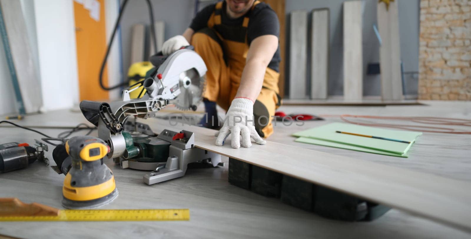 Repairman sawing laminate panels floor in room by kuprevich