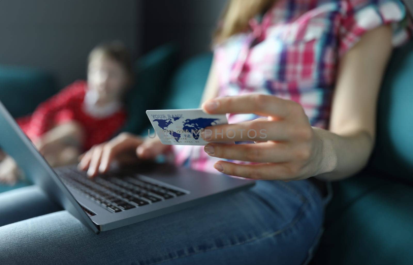 Mom is sitting on couch with laptop and credit card by kuprevich