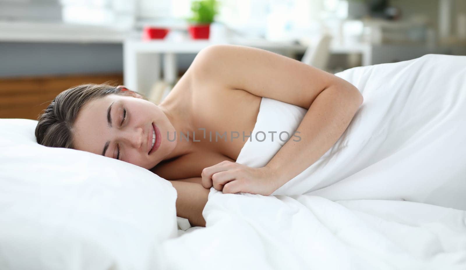 Sleeping beautiful girl is lying in bed and smiling. Regeneration and energy boost. Day off in soft bed. Reluctance to wake up from morning sleep. Comfortable stay at home quarantine