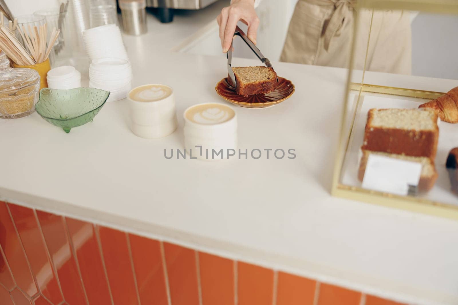 Close-up of female waitress hands putting a delicious dessert on a plate standing behind bar counter