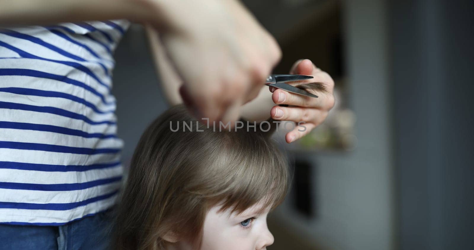 Woman doing haircut to child in an apartment by kuprevich
