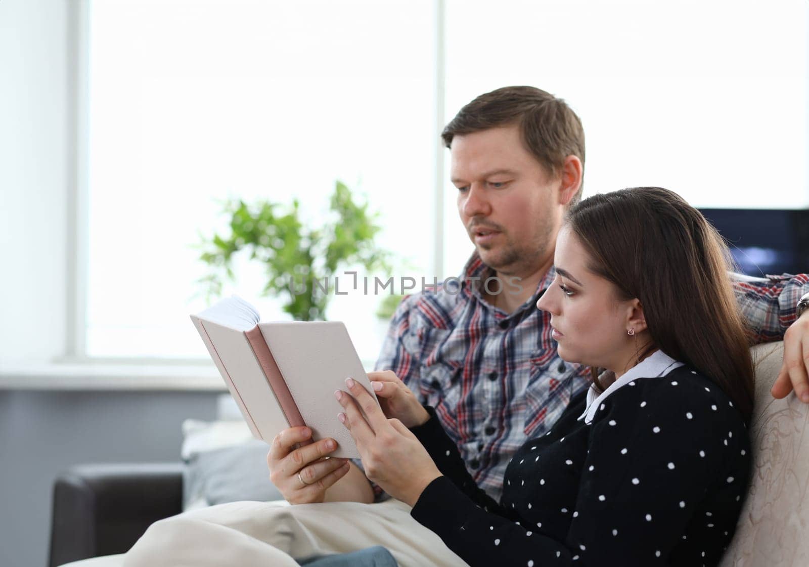 Couple sitting at home and reading book together by kuprevich
