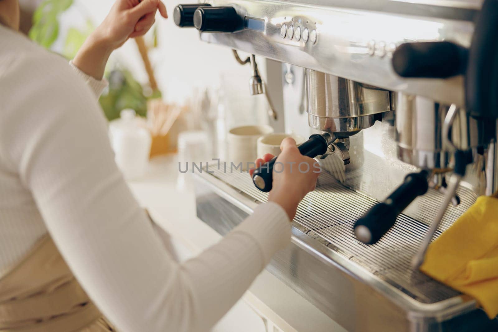 Close up of female barista making coffee in a coffee machine while working in cafe by Yaroslav_astakhov