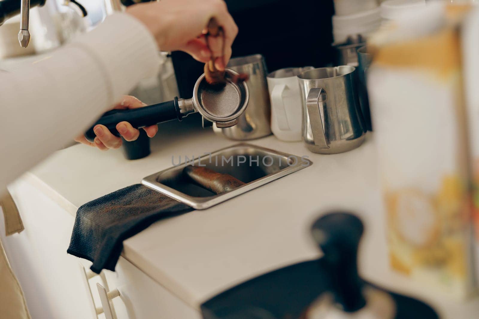 Close up of professional barista is cleaning and drying a filter holder after using by Yaroslav_astakhov
