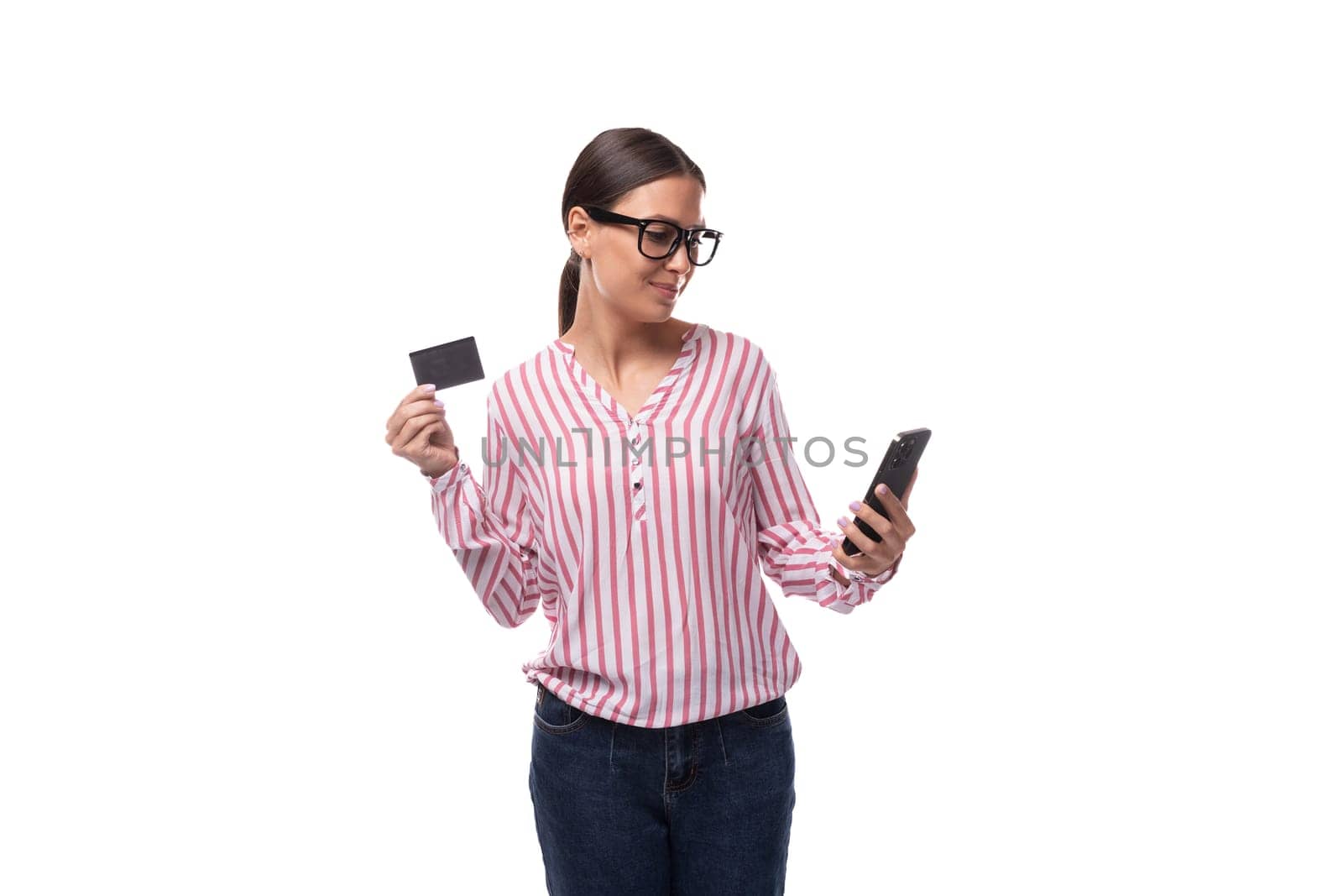 young adorable cute brunette office woman with ponytail holding smartphone and credit card for online payment.