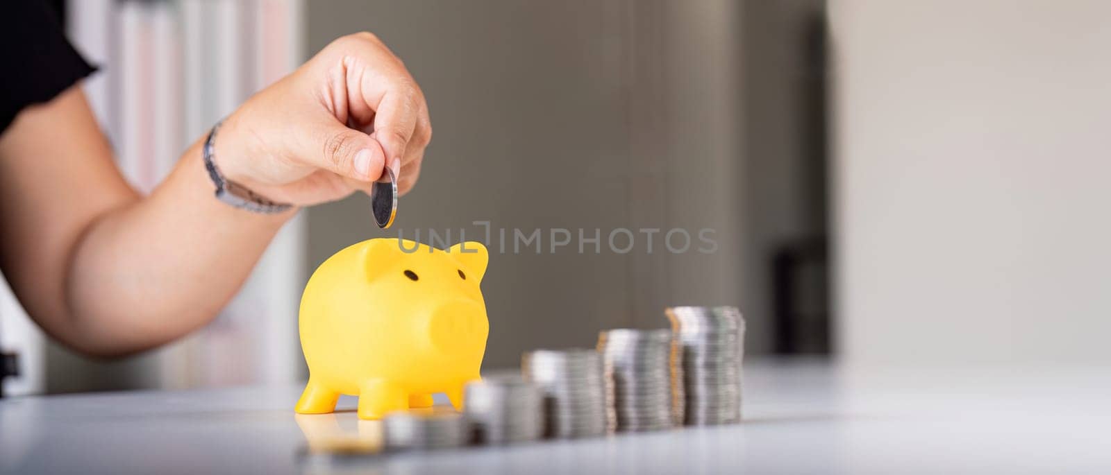 Woman hand putting coins in a piggy bank for save money and saving money concept.