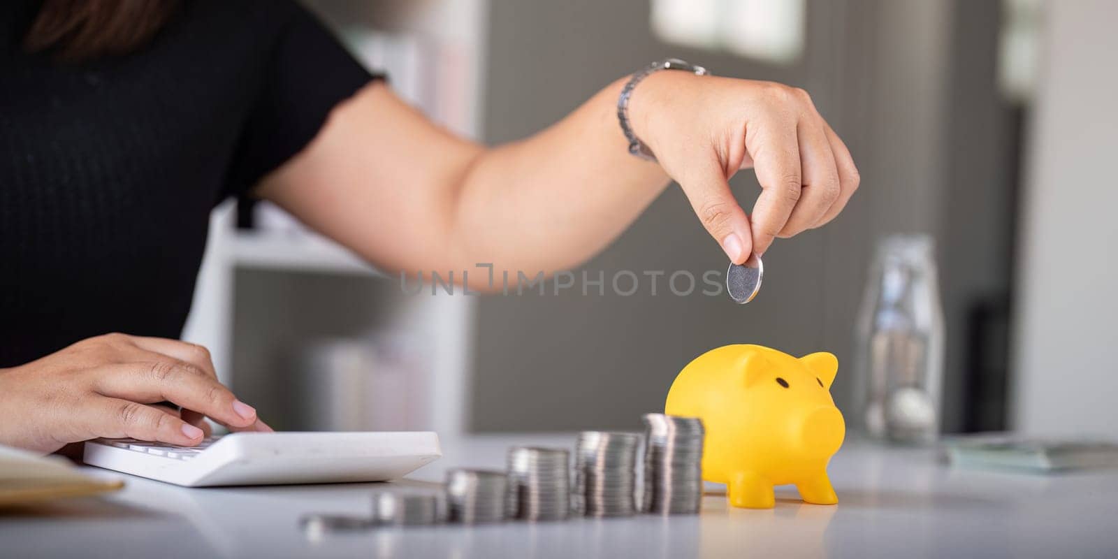 Woman hand putting coins in a piggy bank for save money and saving money concept.