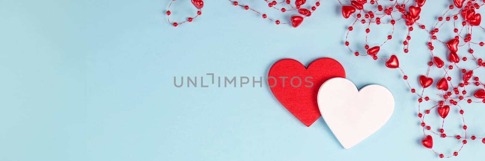 banner of Valentine's Day background. Two hearts with red confetti, beads with hearts on pastel blue colors. Valentine's Day concept. Flat lay. Top view. by Leoschka
