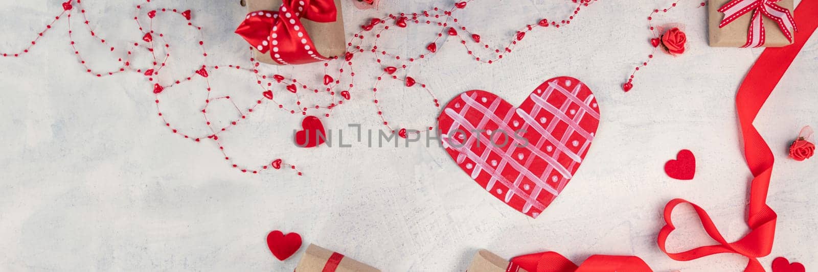 banner of heart from a red ribbon, gifts with a red ribbon and red hearts on a white stone background. Valentine's day background. Valentine's day concept. Flat lay. Top view
