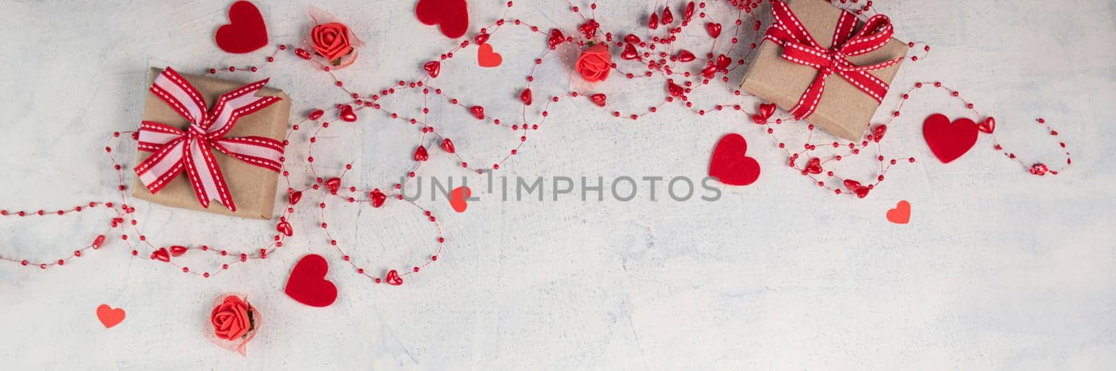 banner of two gifts with red ribbon on white textured background with red beads with hearts. background for valentine's day with space for your text. Soft focus. flat lay