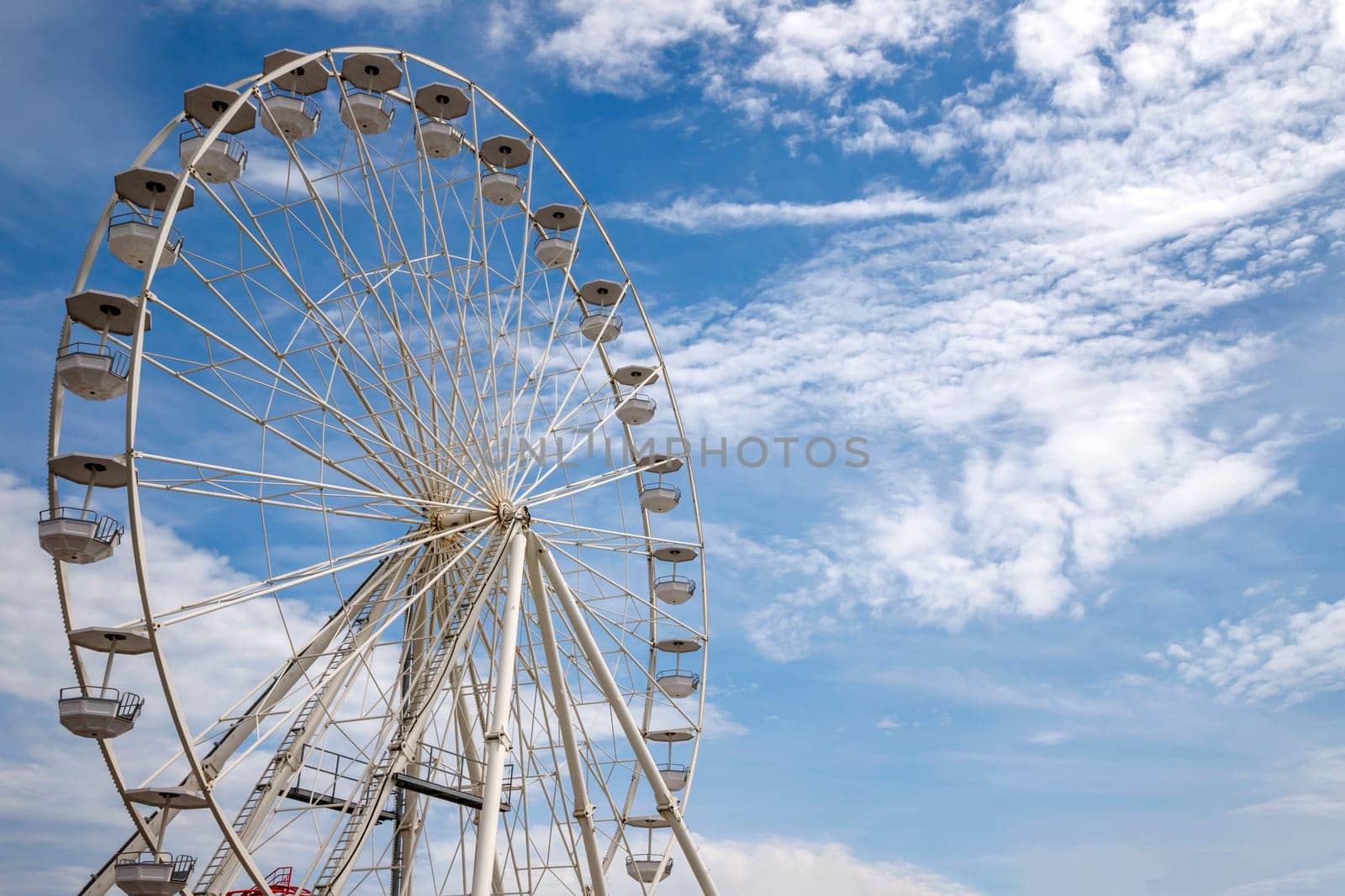 Ferris wheel an amusement park funfairs attraction with a cloudy blue sky by EdVal