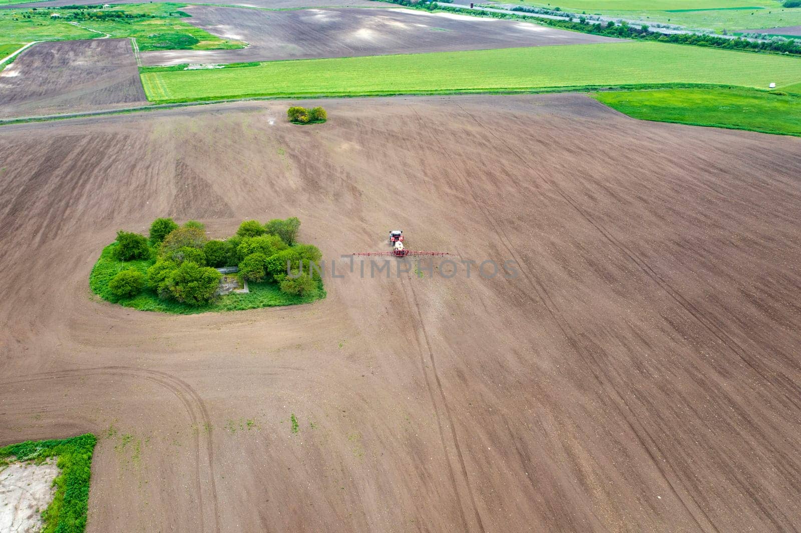 Aerial view of tractor spraying aerosol on a grain fields by EdVal