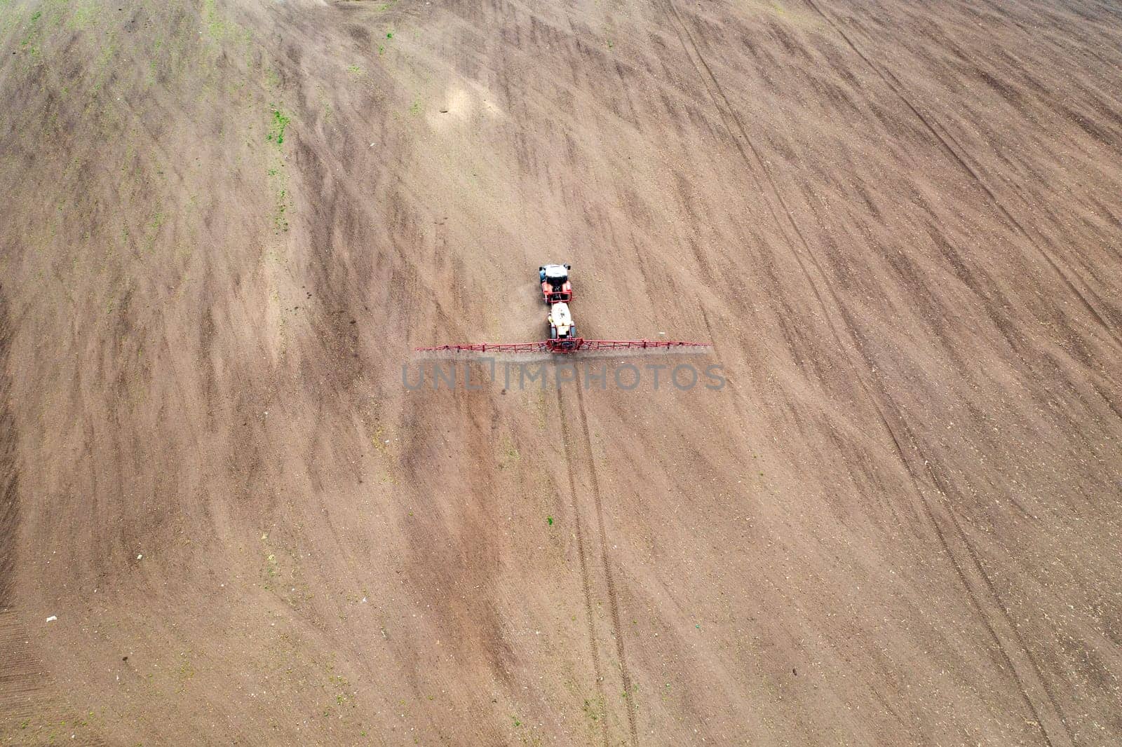 Aerial view of tractor spraying aerosol on a grain fields