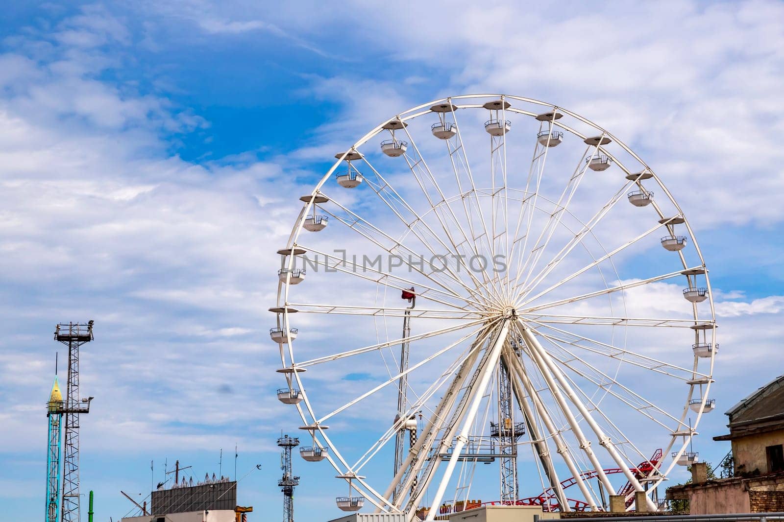 Ferris wheel an amusement park funfairs attraction with a cloudy blue sky by EdVal