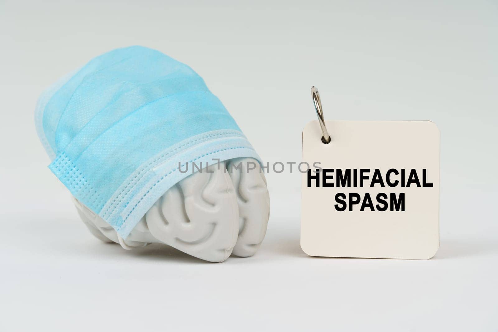 Medical concept. On a white surface next to the brain there is a notepad with the inscription - Hemifacial spasm