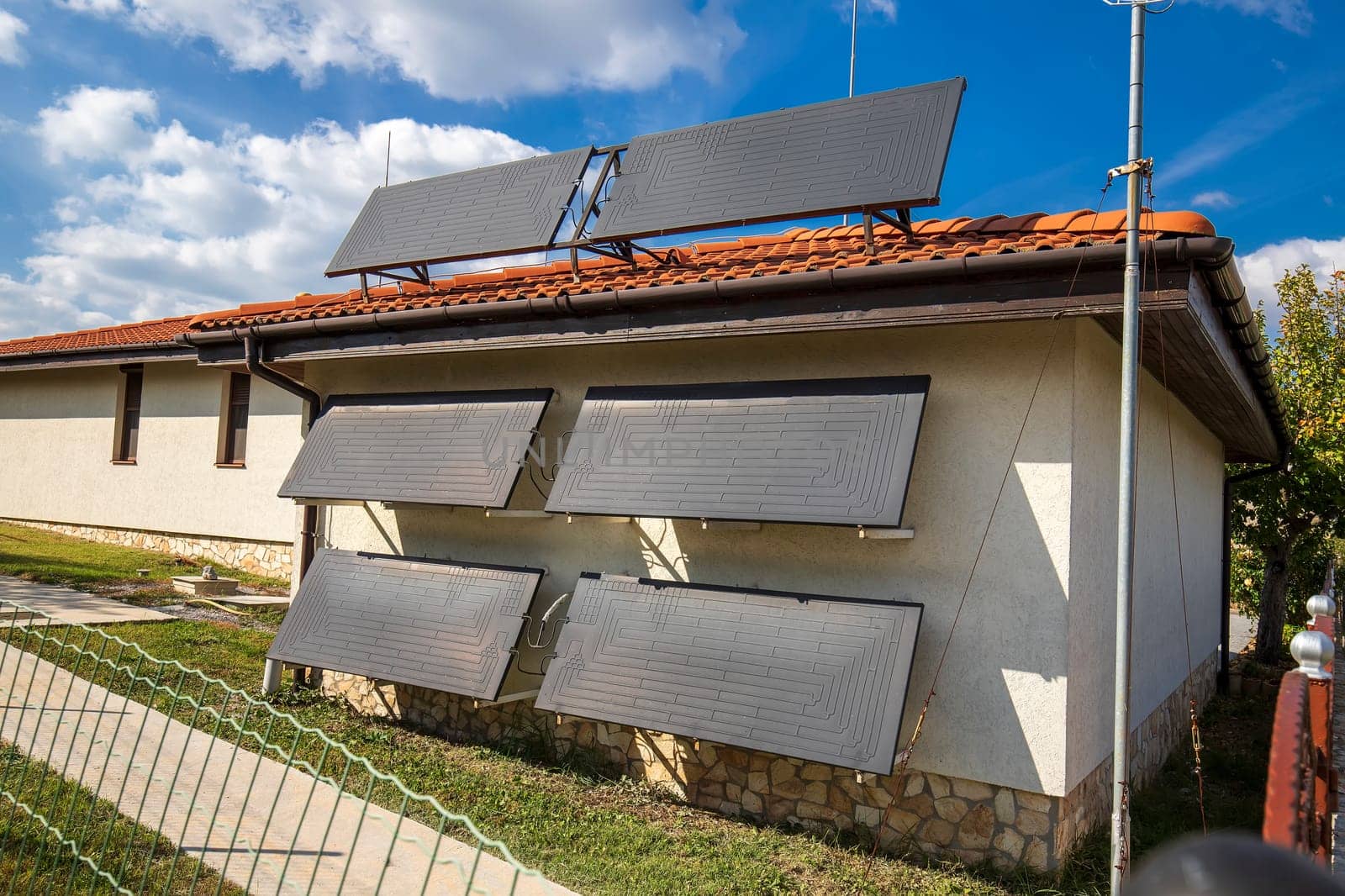 A new modern solar water heater was installed on the wall and roof of a house for heating of water.  by EdVal