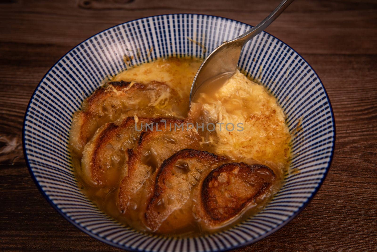 Classic French onion soup baked with cheese croutons sprinkled with fresh thyme, close up view, High quality photo