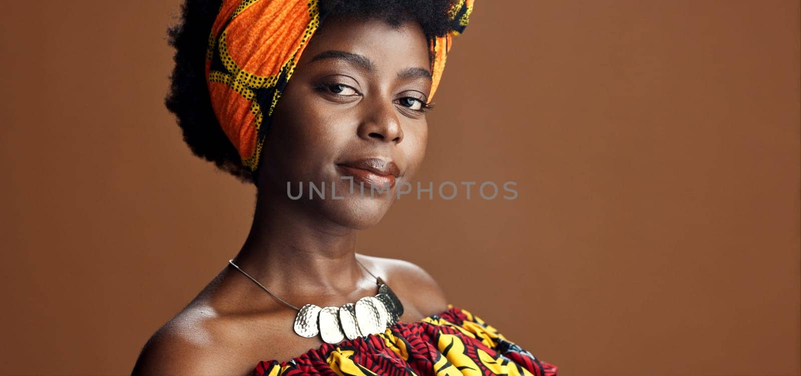 Culture, African fashion or face of black woman in studio on a brown background for trendy style. Unique, beauty or model with confidence, pride or afro posing in wrap, clothes or traditional outfit.