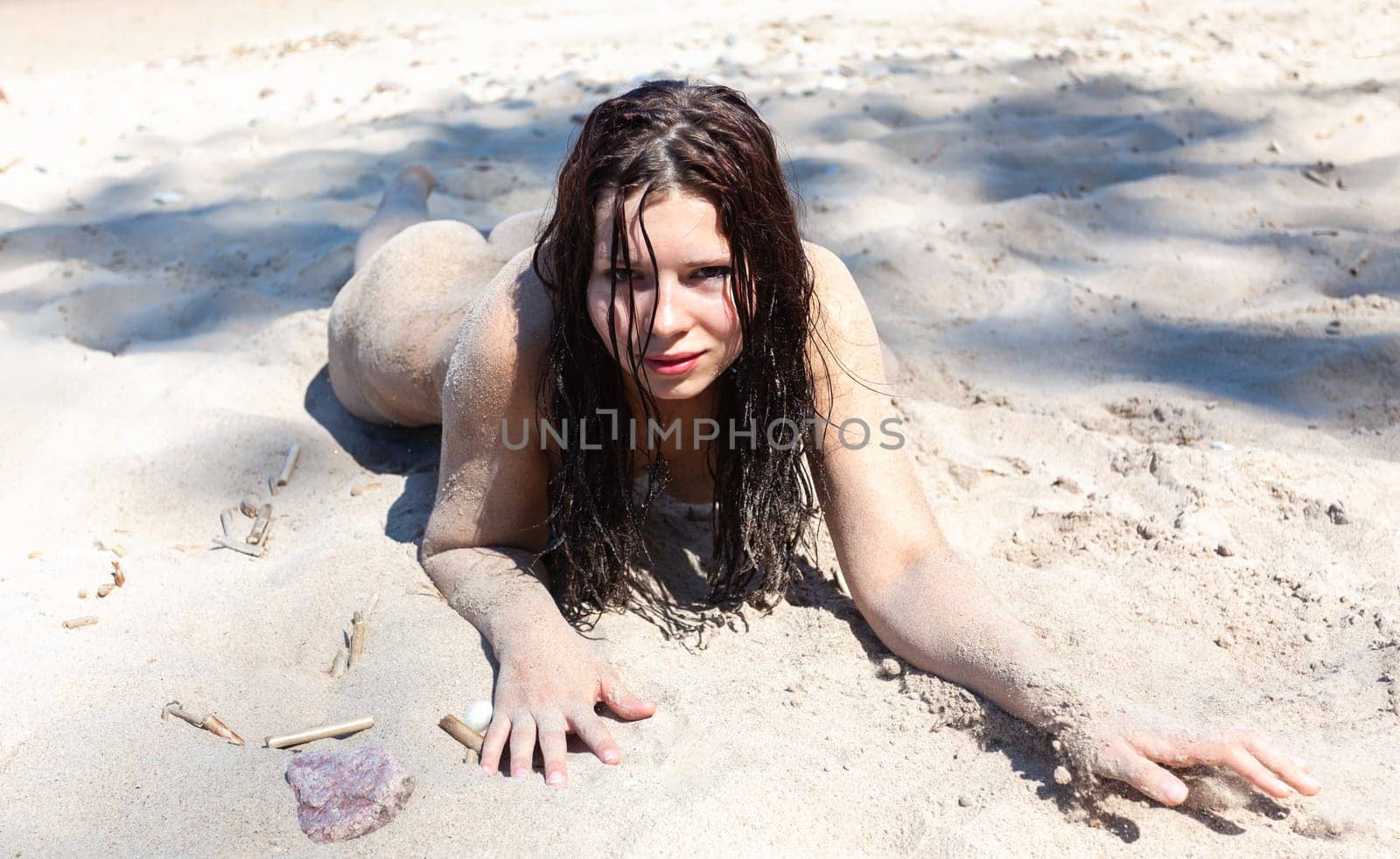 Nude woman with body covered by sand on sea coast by palinchak