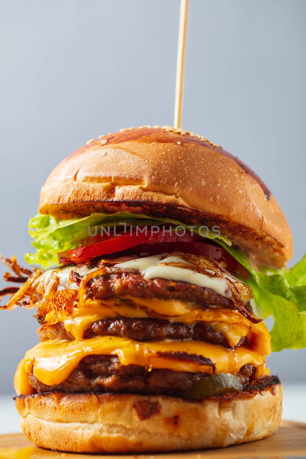 Loaded cheeseburgers three triple, stacked patties stacked high with layers of cheese, lettuce, and tomato. Tall cheeseburger by senkaya