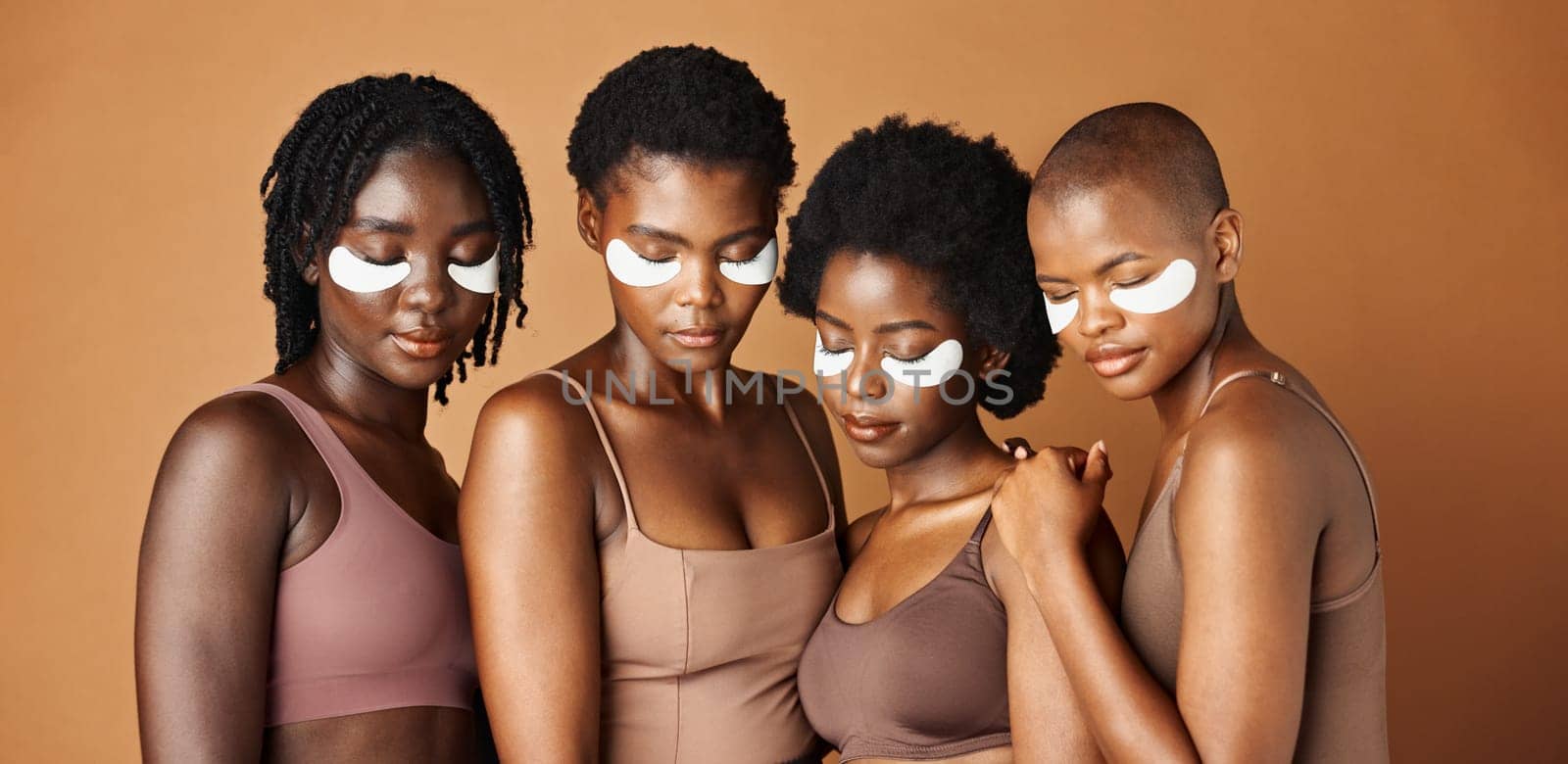 Happy black woman, eye patches and skincare for beauty, epilation or anti aging against a brown studio background. Group portrait of African female people or model in dermatology, health and wellness.