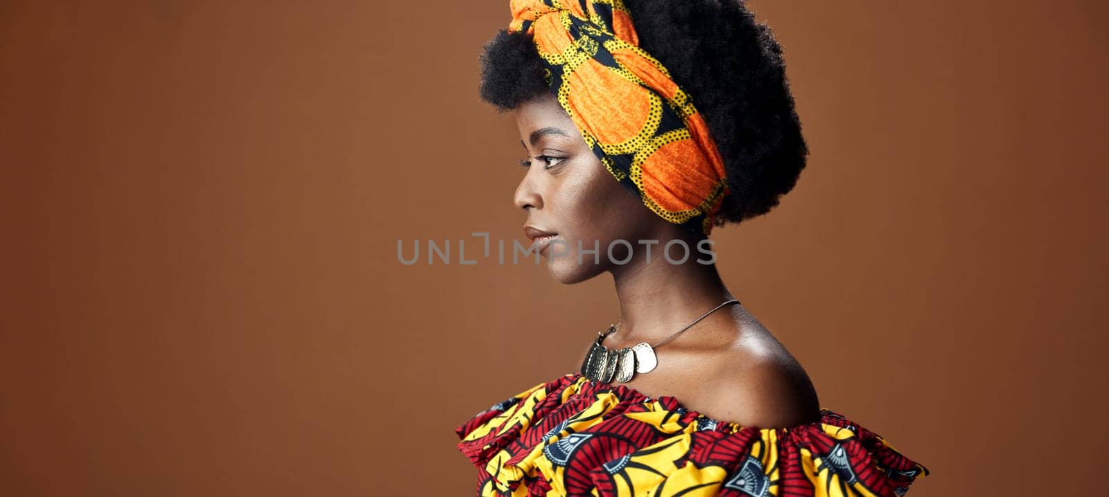 Culture, African fashion or face of black woman in studio on a brown background for trendy style. Unique, beauty or model with confidence, pride or afro posing in wrap, clothes or traditional outfit by YuriArcurs