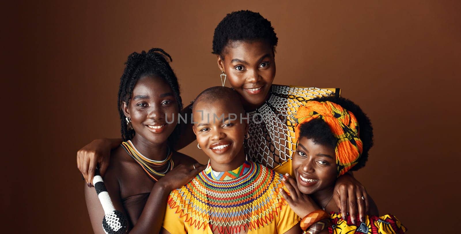 Fashion, beauty and heritage with group of black women in studio on brown background together for support. Portrait, smile and culture with happy African people in clothes of tradition for community.