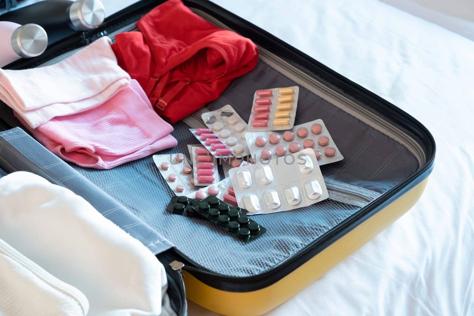 Travel concept. opened packed suitcase on bed in hotel room, pills and medicine