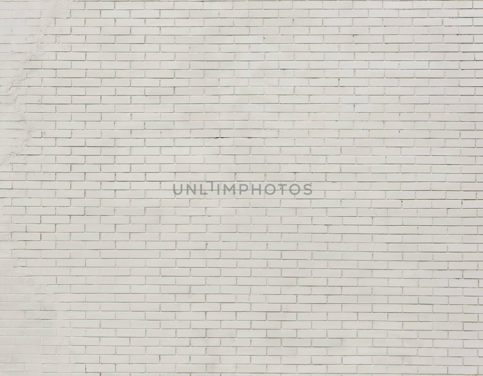 Painted brick wall and weathered sidewalk .