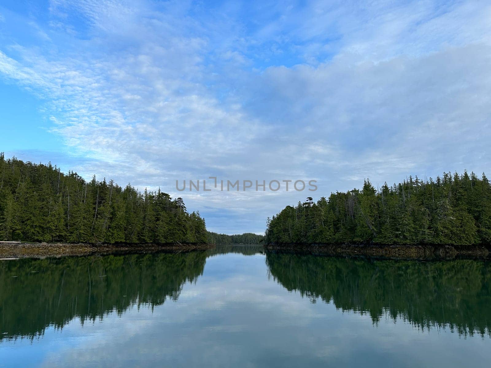 Entrance to a bay between two small island with blue skies and streaky clouds along the Central Coast of British Columbia by Granchinho