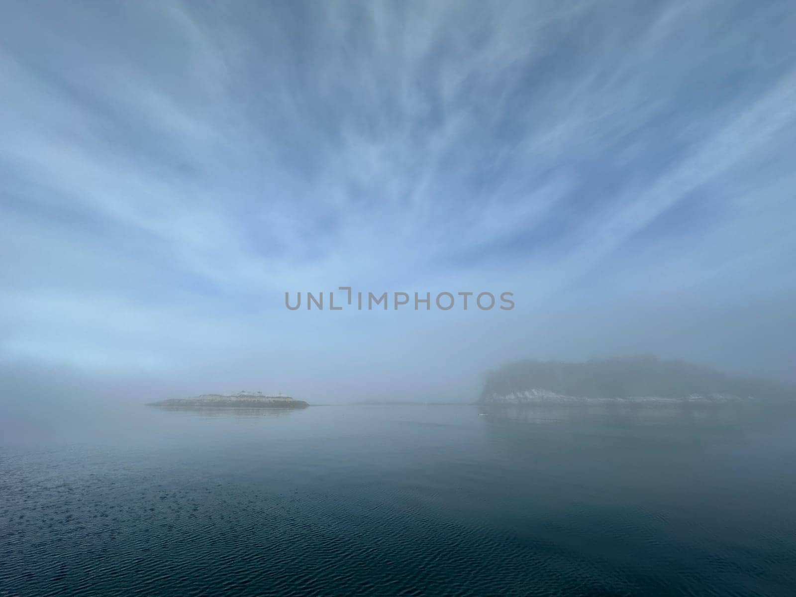 Morning fog with islands and blue, cloudy skies reflecting on the water. Near Stryker Island, British Columbia by Granchinho