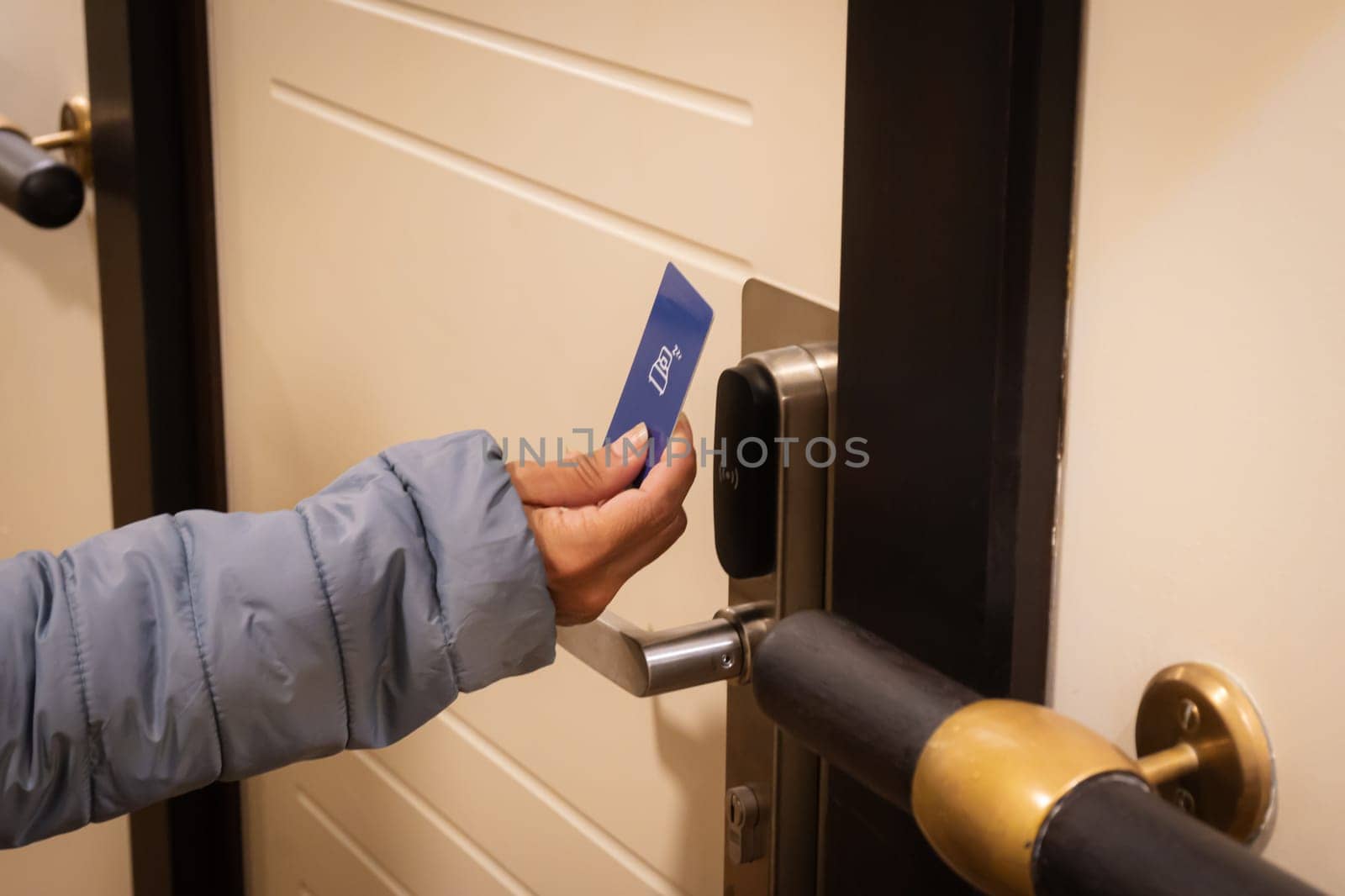 Close-up of a hand holding a key card to unlock a hotel door.