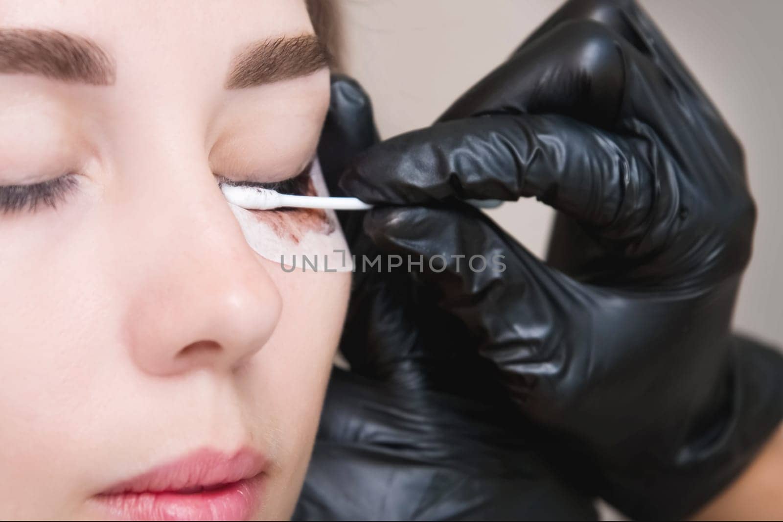 A makeup artist performs the procedure of lamination and coloring of eyelashes on a beautiful woman in a beauty salon. Eyelash extensions. Client and master, beauty procedures