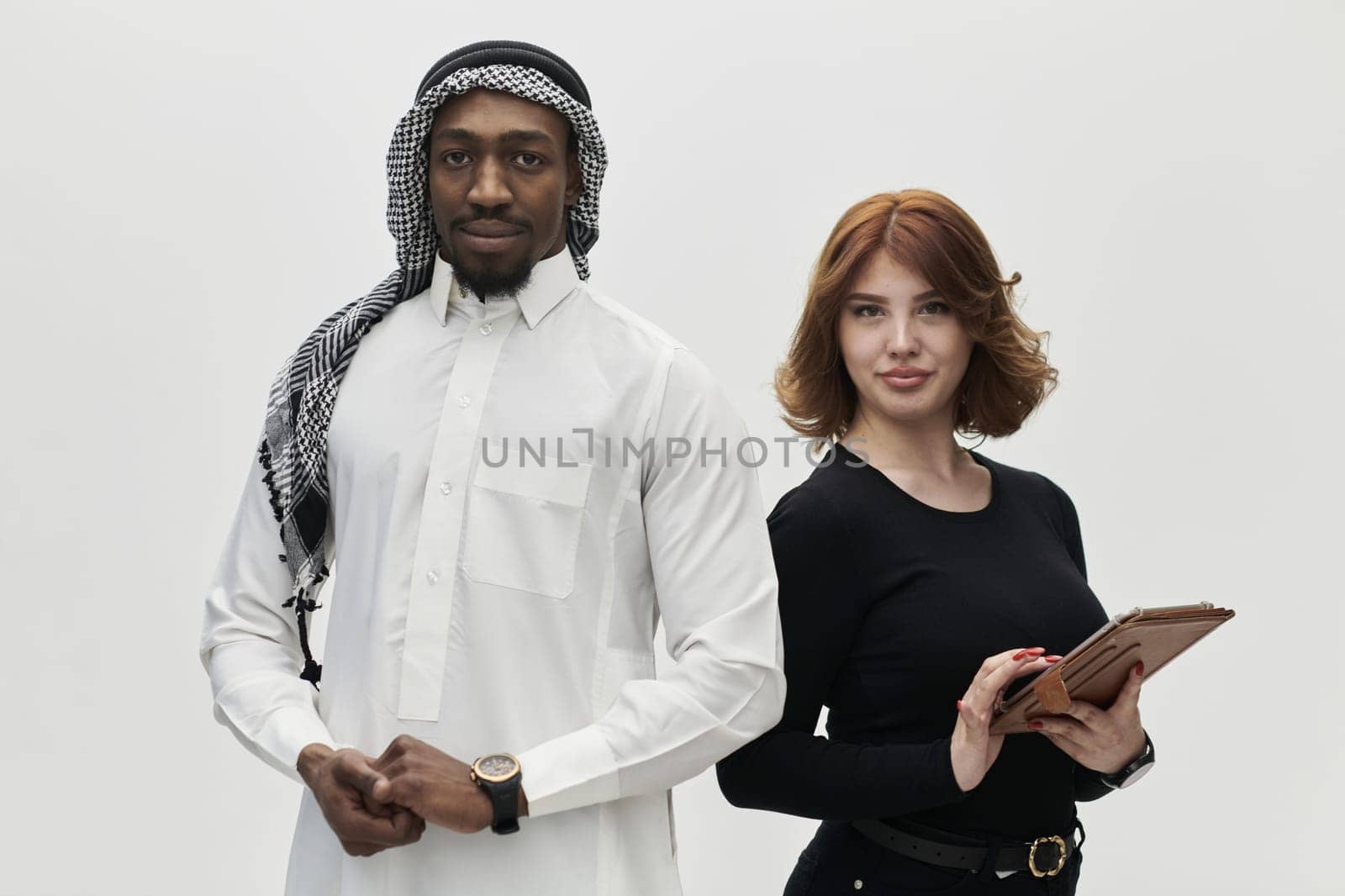 Arabic entrepreneur and a businesswoman, exuding confidence and unity, pose together against a clean white backdrop, symbolizing a dynamic partnership characterized by ambition, innovation, and collaborative success in the business realm.