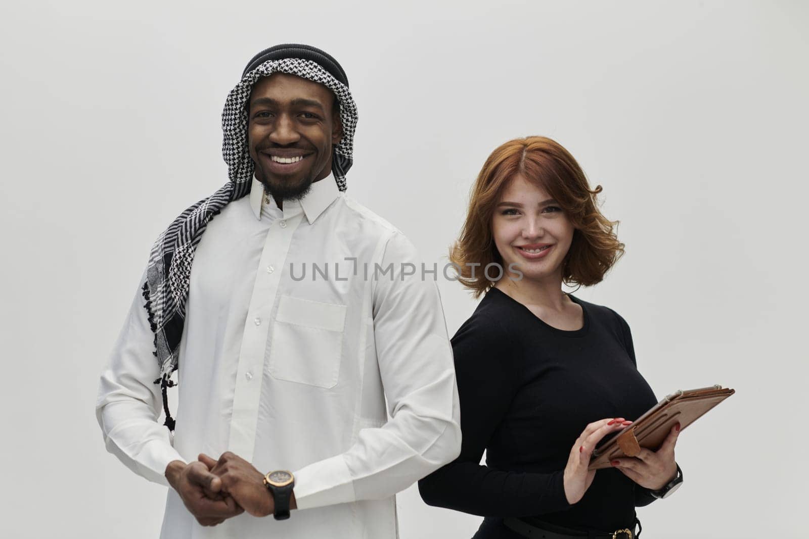 Arabic entrepreneur and a businesswoman, exuding confidence and unity, pose together against a clean white backdrop, symbolizing a dynamic partnership characterized by ambition, innovation, and collaborative success in the business realm.