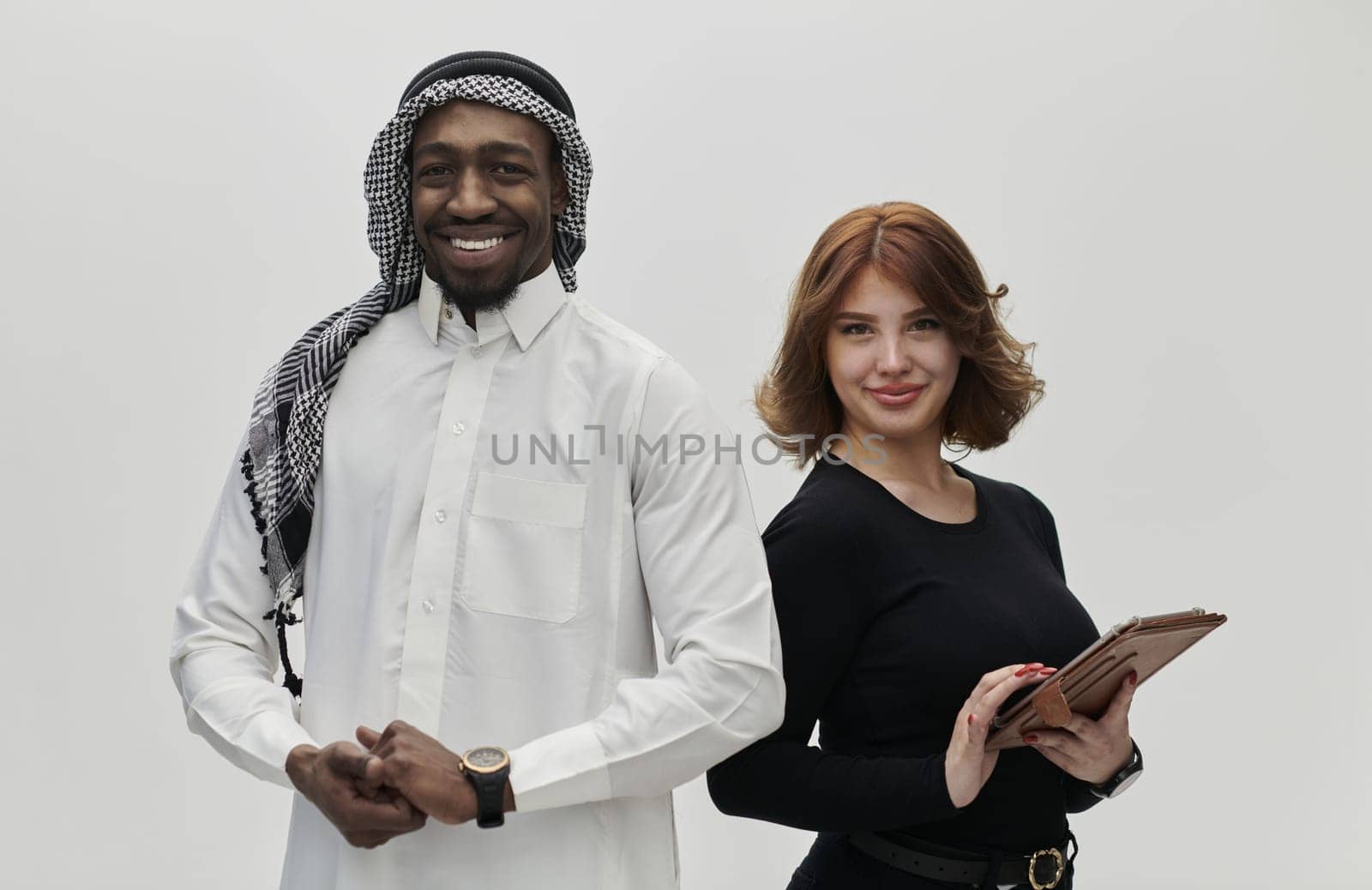 Arabic entrepreneur and a businesswoman, exuding confidence and unity, pose together against a clean white backdrop, symbolizing a dynamic partnership characterized by ambition, innovation, and collaborative success in the business realm by dotshock