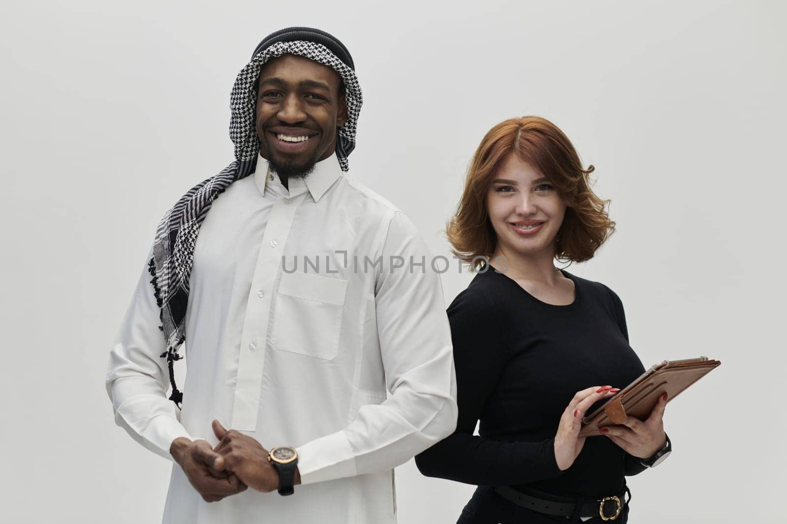 Arabic entrepreneur and a businesswoman, exuding confidence and unity, pose together against a clean white backdrop, symbolizing a dynamic partnership characterized by ambition, innovation, and collaborative success in the business realm by dotshock