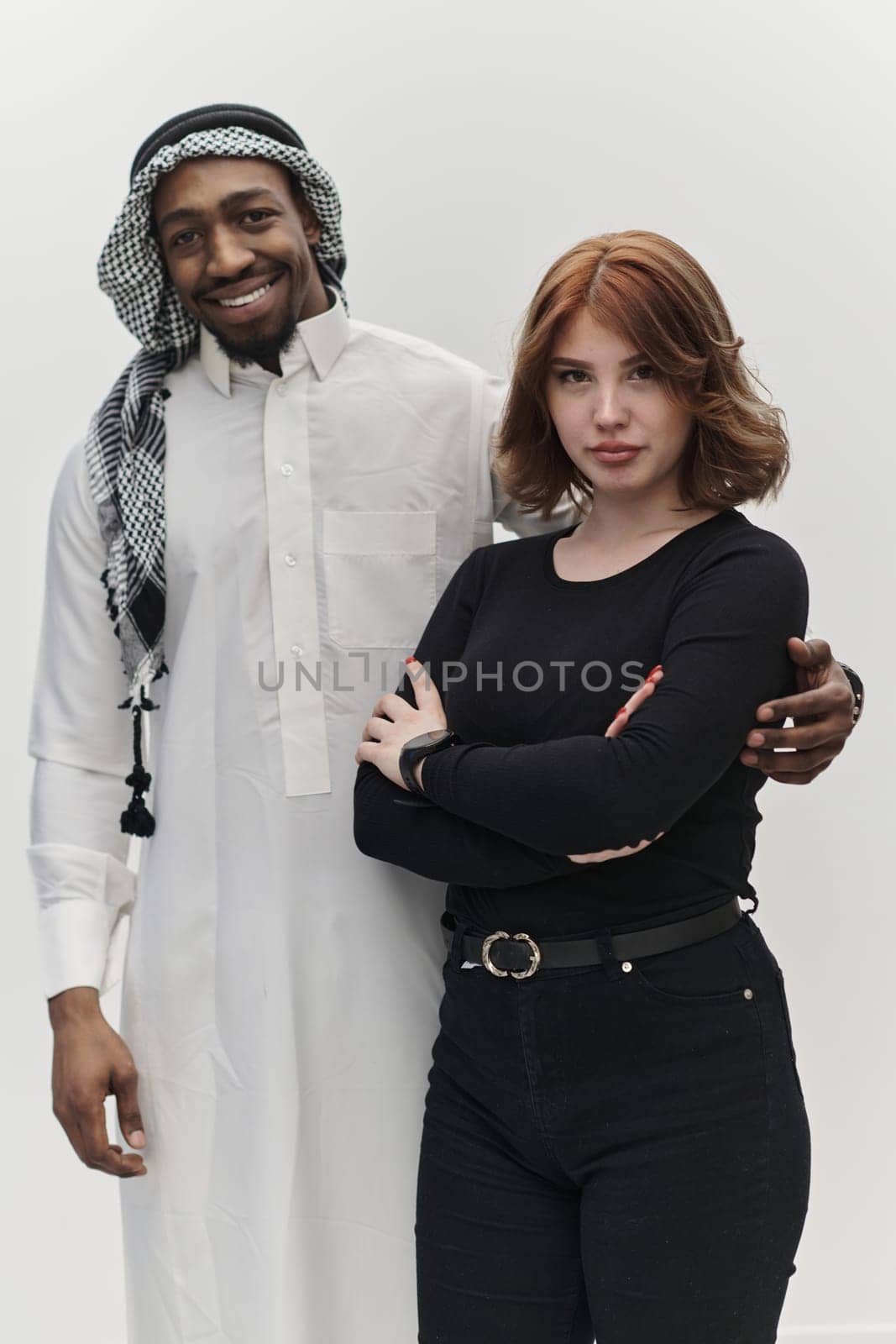 Muslim entrepreneur and a contemporary red-haired girl strike a pose together against a clean white background, embodying confidence, diversity, and a dynamic entrepreneurial spirit in their partnership.