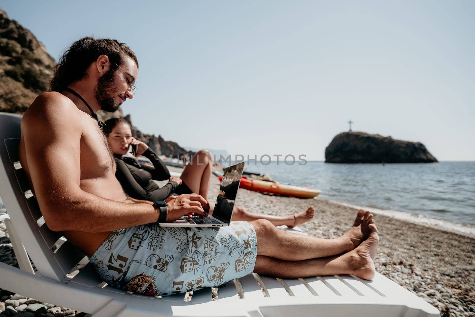 Man woman laptop sea. Working remotely on seashore. Happy successful couple, freelancers working on sea beach, relieves stress from work to restore life balance. Freelance, remote work on vacation by panophotograph